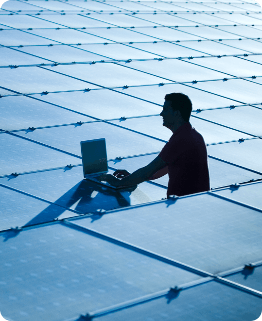 Man with laptop working in large solar panel installation